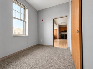 A room with a large window, carpeted floor, and a view of a building outside. - Flash Offer Cozy 1-bedroom condo in adorable Minneapolis for 1859/Month (Minneapolis)