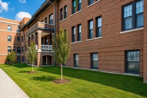 A multi-story brick building with a covered outdoor seating area and a well-maintained lawn. - Flash Offer Cozy 1-bedroom condo in adorable Minneapolis for 1859/Month (Minneapolis)