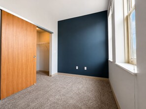 A room with a wooden closet, a dark blue wall, and a window. - Flash Offer Cozy 1-bedroom condo in adorable Minneapolis for 1859/Month (Minneapolis)
