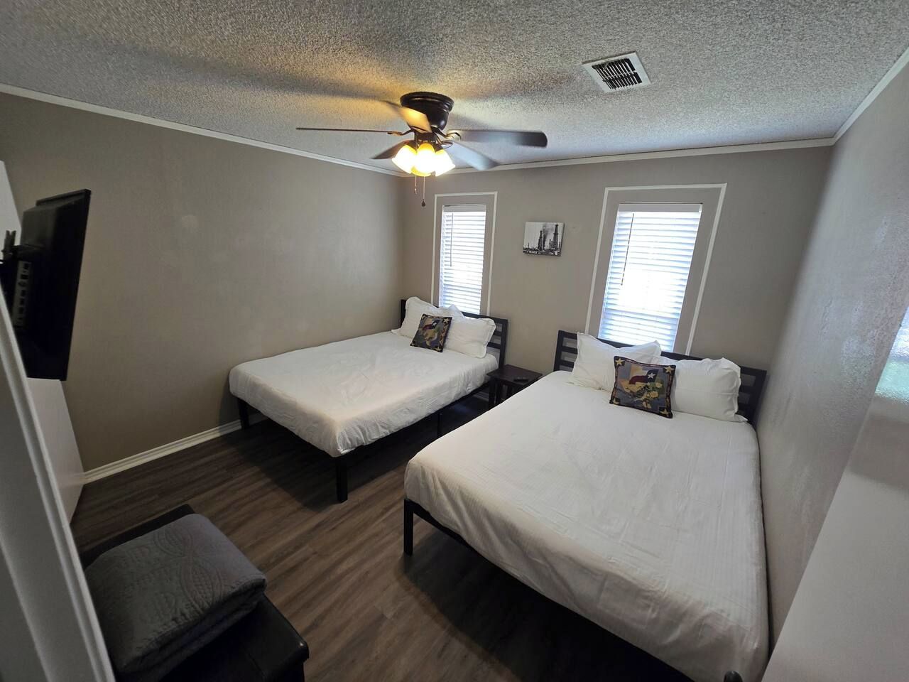 A bedroom with two beds, a ceiling fan, and a window with blinds.