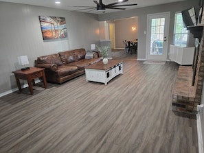 A spacious living room with a brown leather sofa, a white coffee table, and a ceiling fan. - Beal Park - 3 bdrm(4 bed) , 2 bath, 2 car garage (Midland)