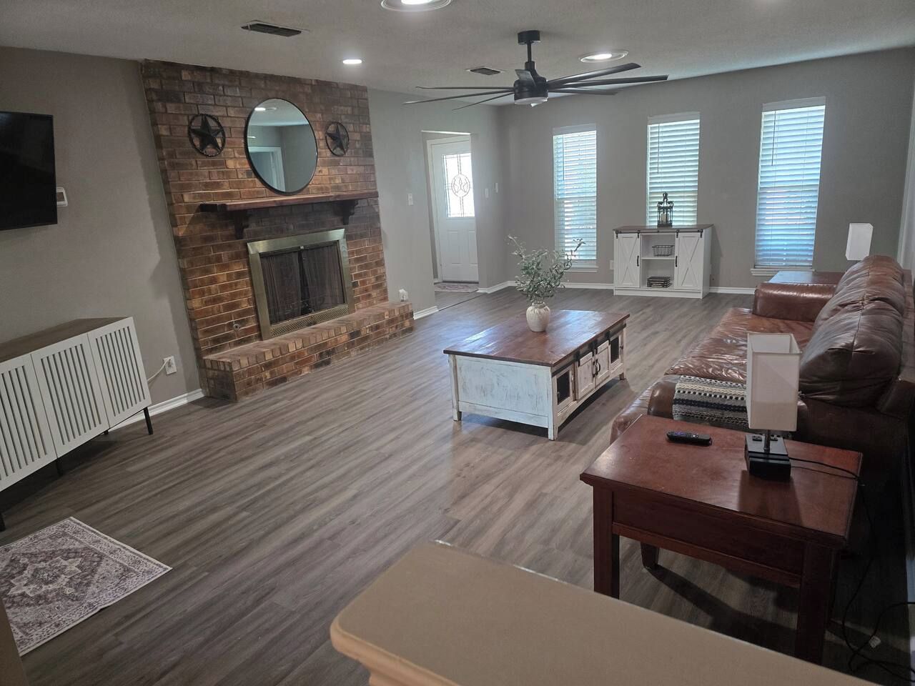 A living room with a fireplace, a ceiling fan, and a leather sofa.