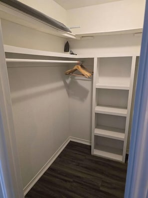 A walk-in closet with white shelving units and a wooden hanger rod. - Beal Park - 3 bdrm(4 bed) , 2 bath, 2 car garage (Midland)