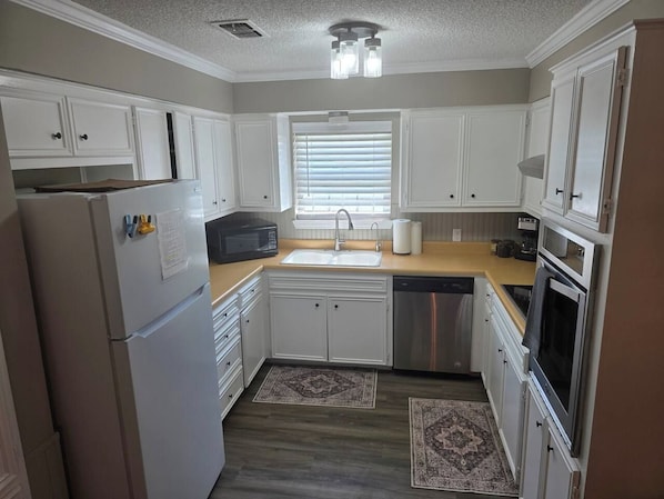 A compact kitchen with white cabinets, a microwave, a sink, and a dishwasher. - Beal Park - 3 bdrm(4 bed) , 2 bath, 2 car garage (Midland)