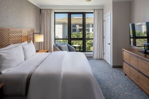 Camera d'albergo con un letto, una scrivania, una televisione e una finestra vista edifici e alberi.