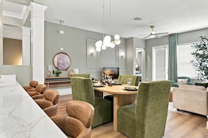 A dining area with a wooden table, green upholstered chairs, and a chandelier. - Designer Luxury 3BR Stunning Lake View Vista Cay (Orlando)