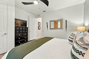 A bedroom with a bed, dresser, television, and a ceiling fan. - Amazing 4BR at Vista Cay With Gorgeous Lake View (Orlando)