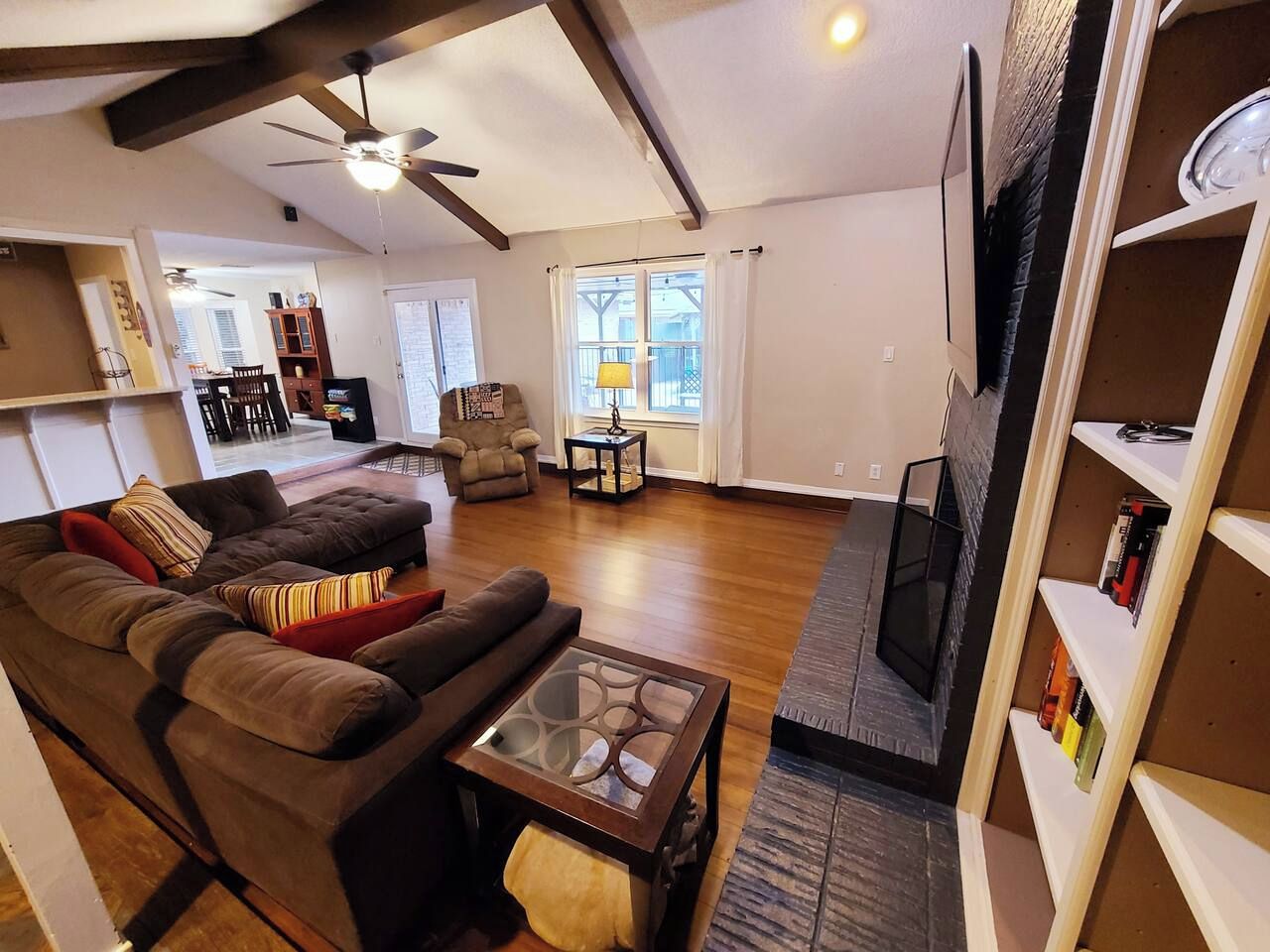 A living room with a sofa set, a coffee table, a television, and a bookshelf.