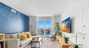 Un salon moderne avec une grande fenêtre, un canapé, une table basse et un mur orné d’une carte.