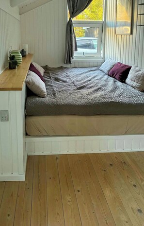 A compact bedroom with a bed, a small table, and a window with curtains. - Nature plot with wild tub near Bratten Strand (Jerup)