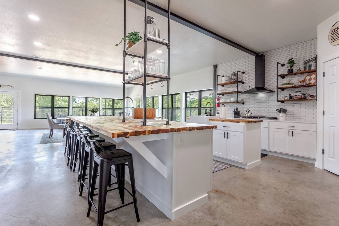 A modern kitchen with a central island, bar stools, and a view of the outdoors.