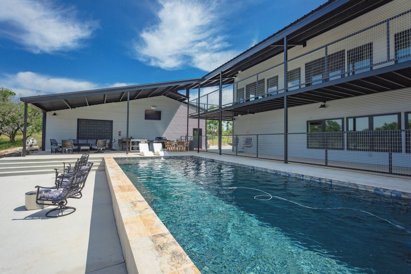 A swimming pool with lounge chairs and a covered patio area.