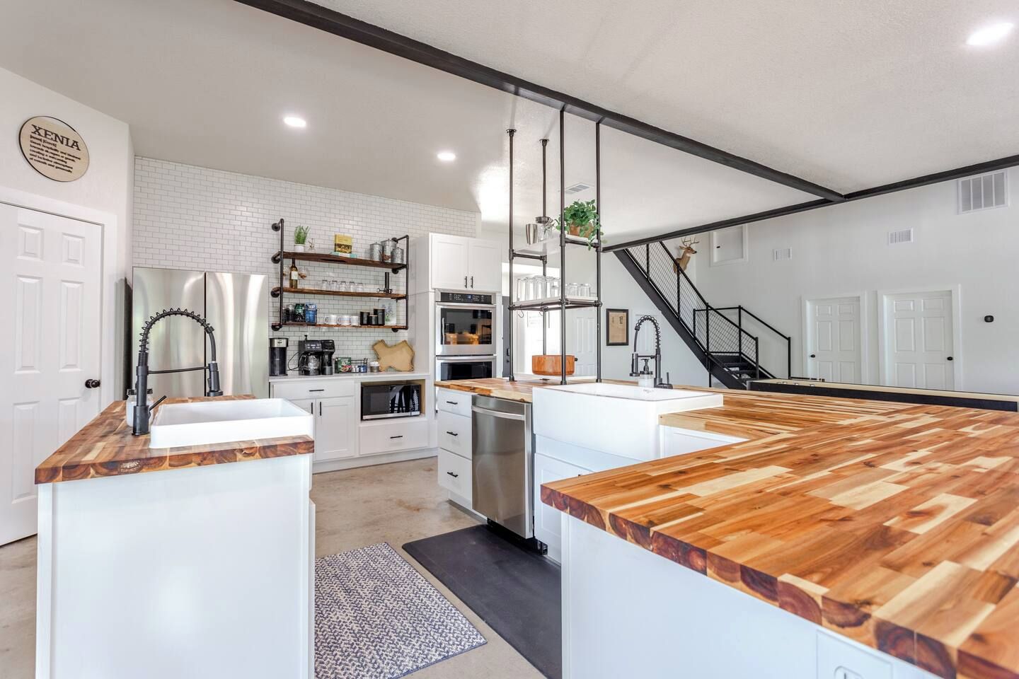 A modern kitchen with white cabinetry, a wooden countertop, and a stainless steel refrigerator.