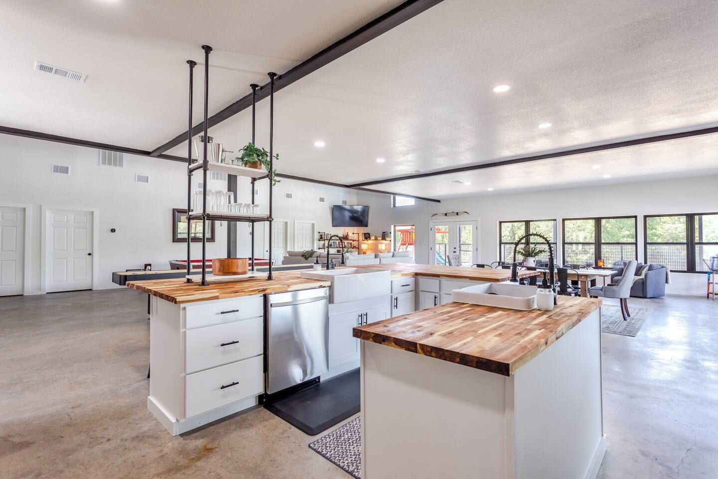 A spacious kitchen with a central island, white cabinetry, and a wooden countertop.