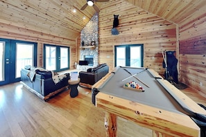 A cozy cabin interior with a pool table, a fireplace, and a sofa. - Twin Bears (Ruidoso)