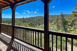 A wooden deck with a view of a forested mountain range. - Twin Bears (Ruidoso)