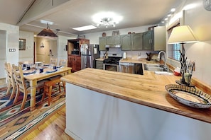 A modern kitchen with a central island, wooden dining table, and chairs. - Gonzo Chalet (Ruidoso)