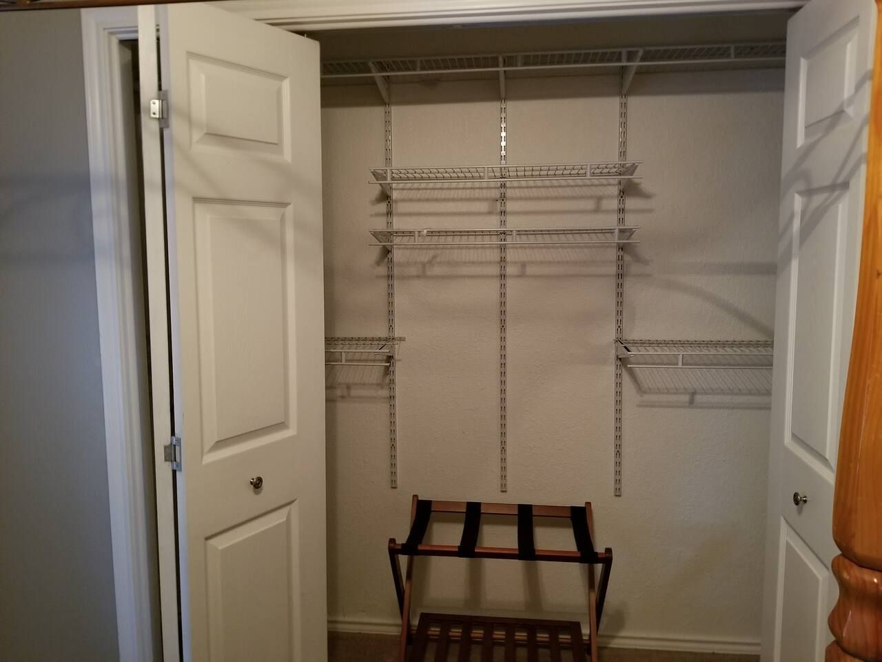 Un dressing avec des étagères en métal et un banc en bois.