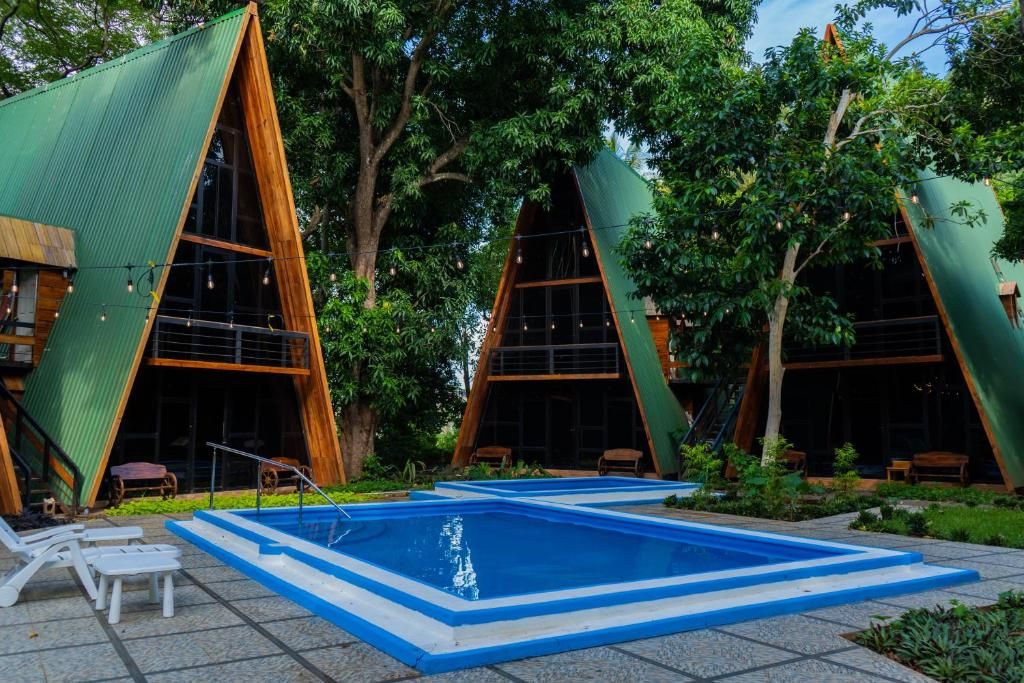 A modern building with a triangular roof design, a swimming pool, and outdoor seating.