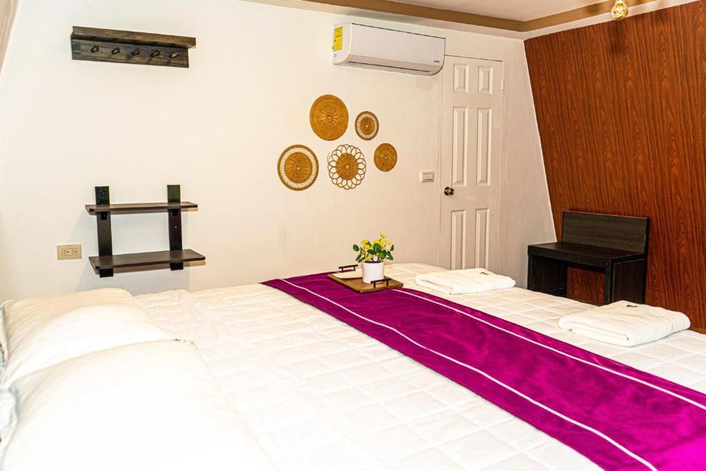 Une chambre d’hôtel comprenant un lit, une table de chevet, une étagère fixée au mur, des éléments décoratifs muraux et un appareil de climatisation.
