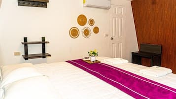 Une chambre d’hôtel comprenant un lit, une table de chevet, une étagère fixée au mur, des éléments décoratifs muraux et un appareil de climatisation.