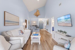 A living room with a sofa, a coffee table, and a television. - Seaside Veranda (New Smyrna Beach)