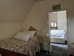 Ein Schlafzimmer mit einem Bett, einem Nachttisch mit Lampe, einer Kommode und einem Spiegel.
