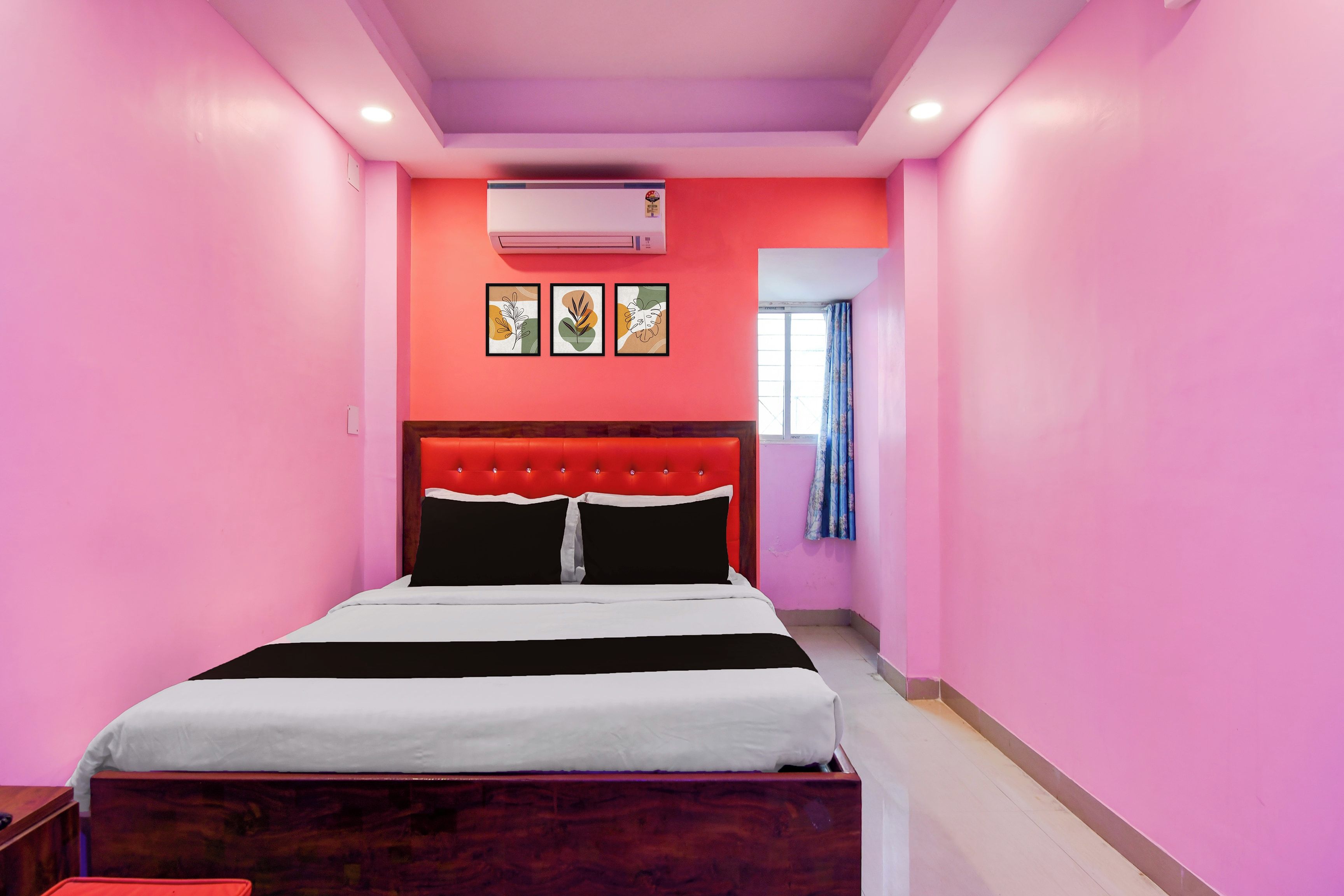 Una habitación de hotel con una cama, una ventana con cortinas y un equipo de aire acondicionado en la pared.