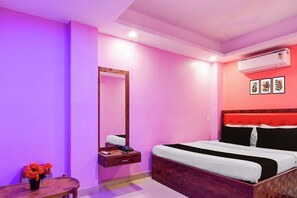 Una habitación de hotel con cama, mesita de noche, espejo y aire acondicionado de pared.