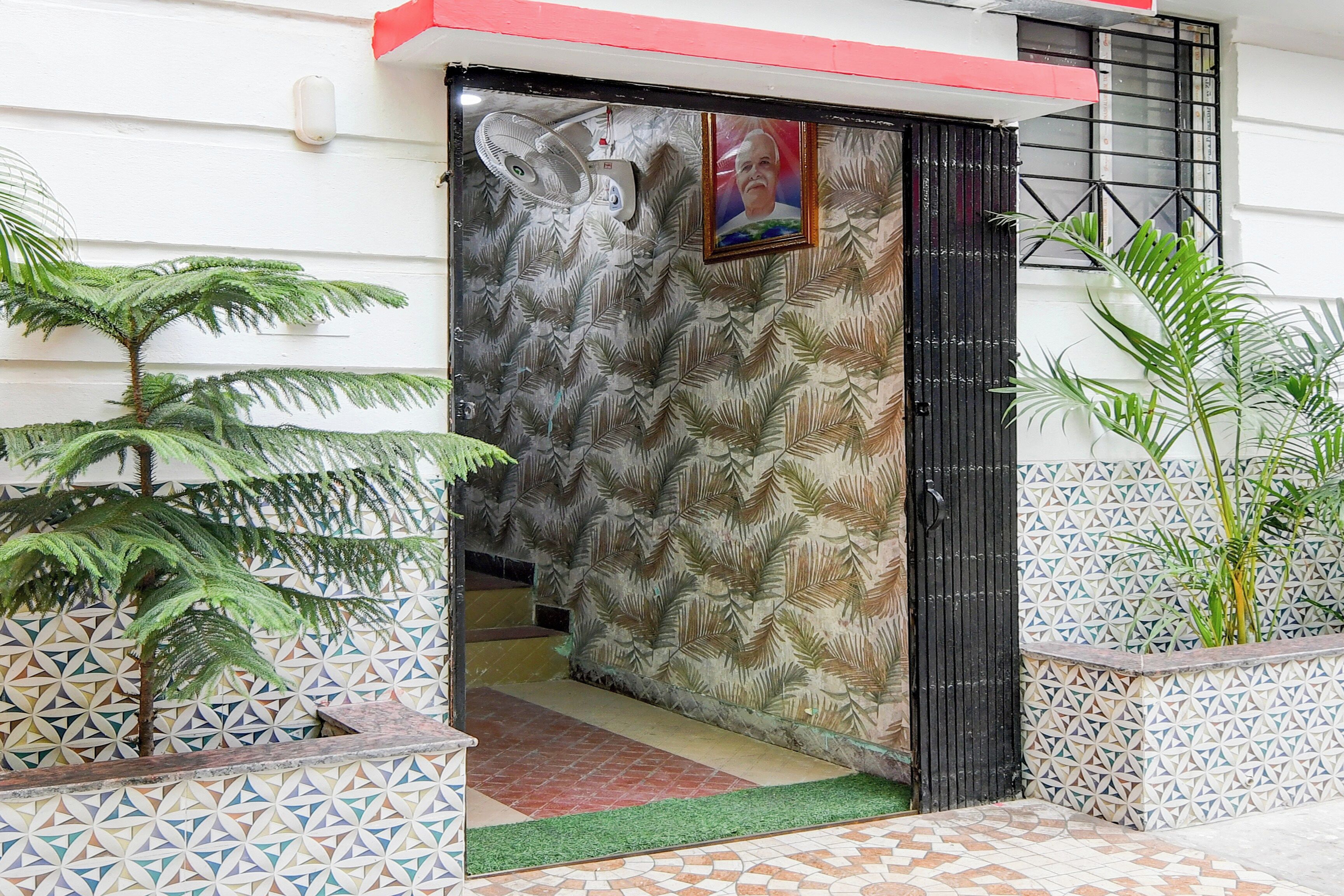 Un vano con un muro decorado, un ventilador y plantas en macetas.