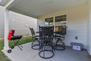 A covered patio with a grill, a table, and four chairs. - The Garden Villa | Tuscaloosa Retreat Sleeps 8 (Tuscaloosa)