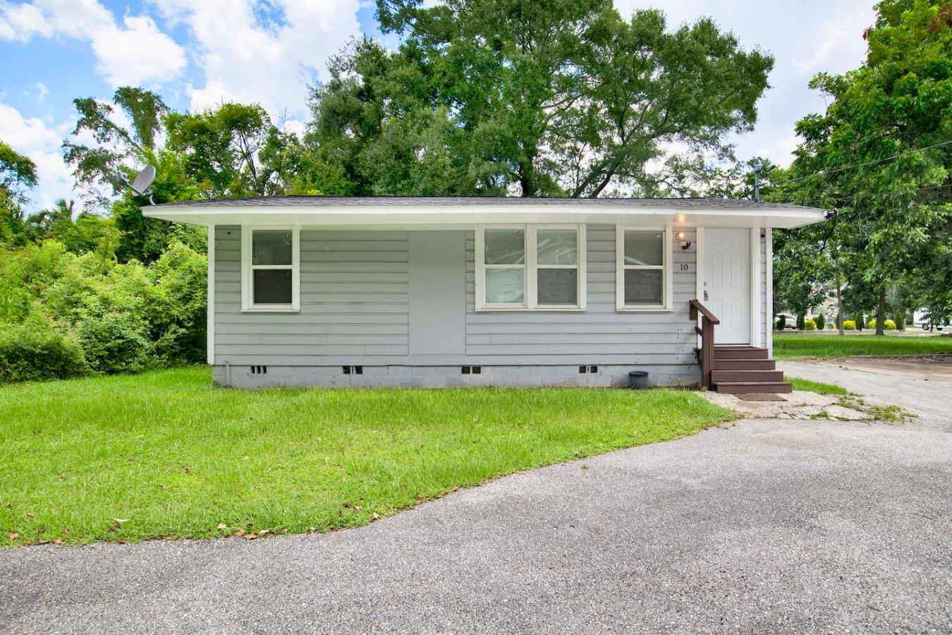 A single-story house with a front porch, a small front yard, and a driveway.