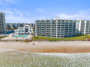 A beachfront hotel with multiple balconies, a swimming pool, and a beach area. - Smyrna Beach Club 218b (New Smyrna Beach)