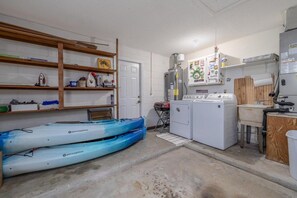 A laundry room with a washing machine, dryer, and stacked kayaks. - Pet friendly home with large backyard (New Smyrna Beach)