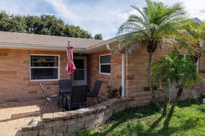 A brick house with a patio, outdoor furniture, and a palm tree. - Pet friendly home with large backyard (New Smyrna Beach)