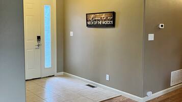 A hallway with a wooden floor, a door with frosted glass, and a wall-mounted sign.