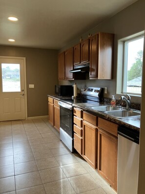 A kitchen with wooden cabinets, a stainless steel stove, a microwave, and a dishwasher.
