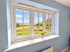 A room with a window overlooking a green field and a clear sky. - Charming 3-Bed Home with Garden and Parking (Cambridge)