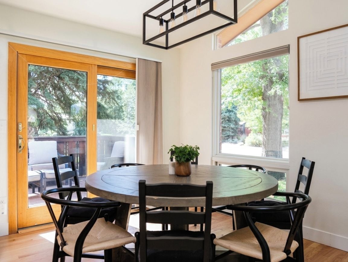A dining area with a round table, chairs, and a potted plant.