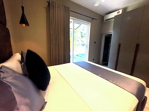 Ein Hotelzimmer mit Bett, einer Hängelampe, einer Schiebetür nach draußen und einer Klimaanlage.