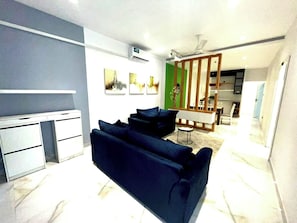 Ein modernes Wohnzimmer mit einer Couch, einem Essbereich mit Tisch und Stühlen sowie einer Küche mit Schränken.
