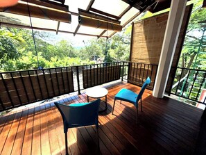An outdoor deck with a wooden floor, two blue chairs, and a small round table. - The Nature Life  (Kandy)