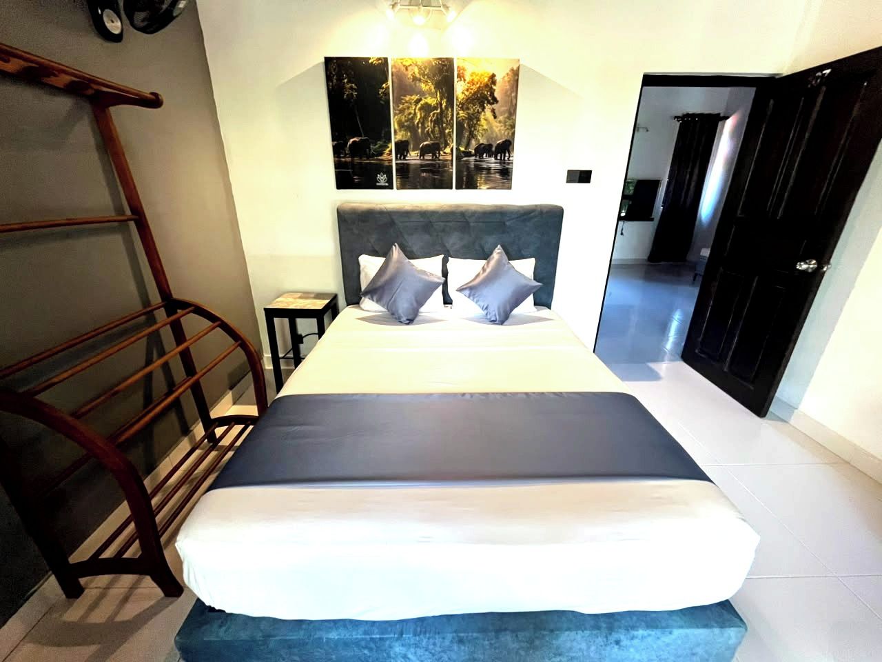 Habitación de hotel con cama, escalera de madera, estante fijado a la pared y puerta que da a otra habitación.
