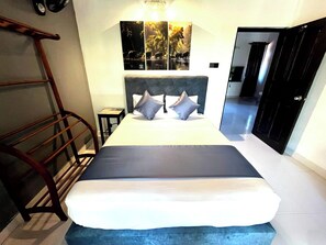A hotel room with a bed, a wooden ladder, a wall-mounted shelf, and a door leading to another room. - The Nature Life  (Kandy)