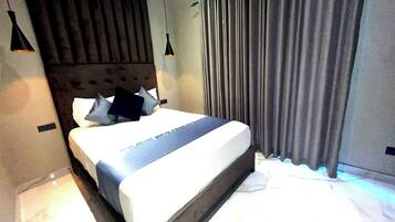 Un dormitorio moderno con una cama grande, cabecera y cortinas.