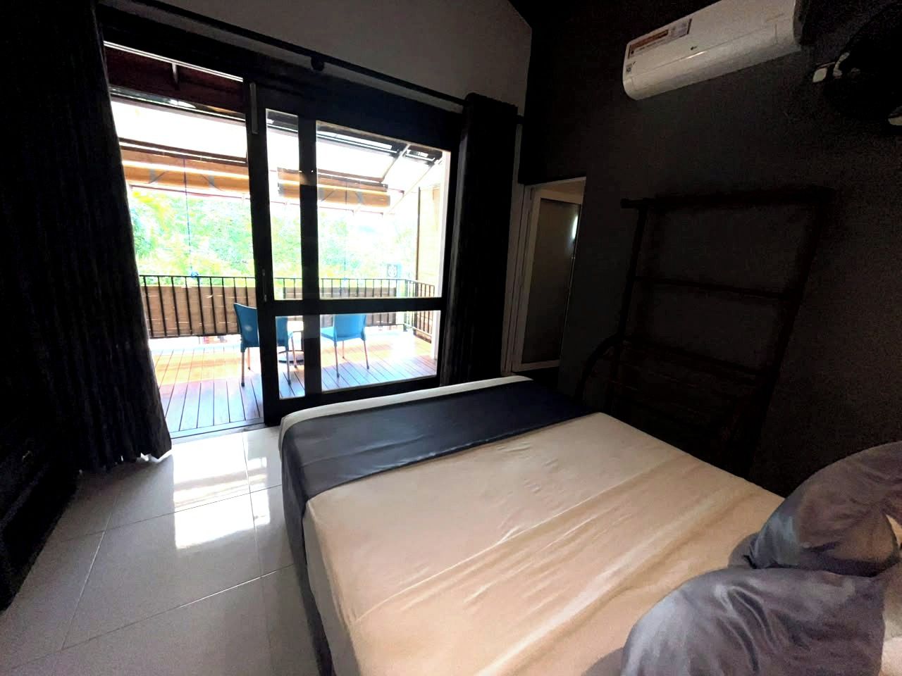 A room with a bed, a window, and a view of an outdoor area with a chair.