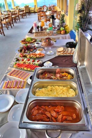 A buffet table with various food items and a dining area in the background. - Hotel Extrema Club (Extrema)