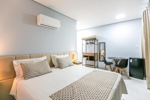 A hotel room with a bed, bedside table, and a small desk area with a chair. - Hotel Extrema Club (Extrema)