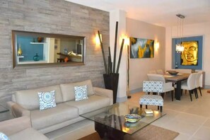 A modern living room with a sofa, coffee table, and dining area. - Oceanfront @Mamitas Beach + Your Own Private Rooftop Paradise w/17' x 15' POOL (Playa del Carmen)