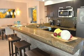 A modern kitchen with granite countertops, stainless steel appliances, and a central island with seating. - Oceanfront @Mamitas Beach + Your Own Private Rooftop Paradise w/17' x 15' POOL (Playa del Carmen)